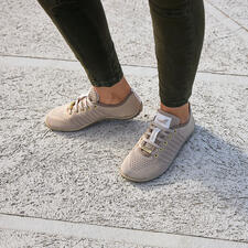 goud Barfuß-leguano Sneaker in beige, gedragen op een ruwe ondergrond.