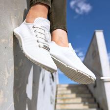 wit Barfuß-leguano Sneaker in wit, gedragen en in de lucht hangend.