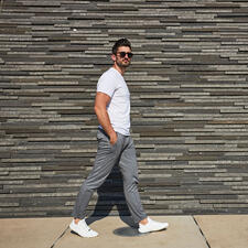 wit Man loopt voor een stenen muur met witte Barfuß-leguano® sneakers.