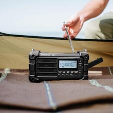 zwart Digitale survivalradio met antenne op een tafel buiten.