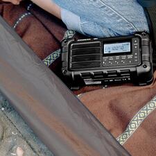 zwart Digitale survivalradio op de grond naast een persoon buiten.