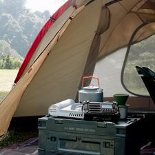 zwart Digitale survivalradio op een tafel in een tent, omringd door kampeerspullen.