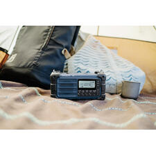 blauw Radio op een deken, naast een kopje en een rugzak.