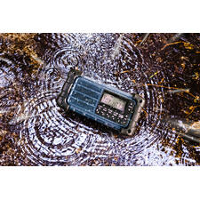 blauw Radio ligt in een plas, waterdruppels eromheen.