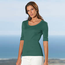 groen Vrouw in groen Wolff-shirt poseert voor een blauwe lucht