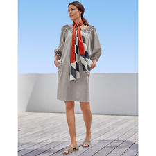 grijs Damesjurk met een kleurrijke sjaal in de hand op het terras.