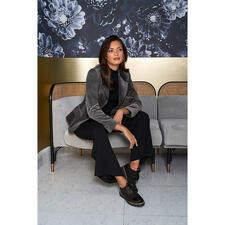 zwart/grijs Vrouw in een wasbare fluwelen blazer met houndstooth patroon op een bank.