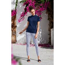 donkerblauw Vrouw poseert onder kleurrijke bloemen in een marinekleurige Clark Ross korte mouwen trui.