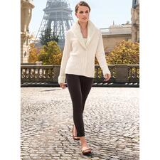 cognac Vrouw in zwarte broek en witte cardigan met kraag, loopt over stenen.