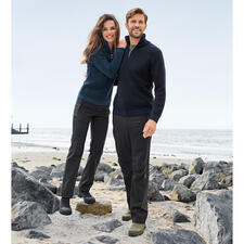 zwart en beige Koppel in zeemanstruien op het strand, omringd door stenen en zee.