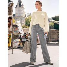 ecru Vrouw draagt een Junghans Basket-pullover met grijze broek en stoffen tas.