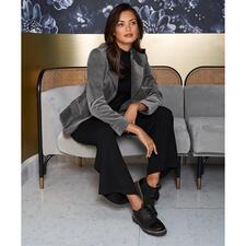 zwart/lichtgrijs Vrouw in een fluwelen houndstooth blazer, zittend op een bank.