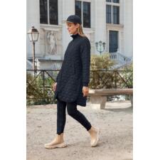 donkerblauw Vrouw in een zwarte gewatteerde jas loopt voorbij een historisch gebouw.