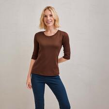 kastanje Vrouw in bruin shirt met korte mouwen poseert lachend voor een neutrale achtergrond.