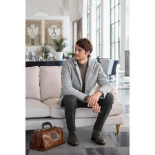 Schipperstrui van kasjmier-piqué Man met grijze kasjmier gewatteerde jas zit op een bank, elegante tas naast hem.