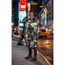 zwart Vrouw draagt een gemêleerde regenponcho in een stad 's nachts.