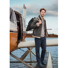 OCONI B3-pilotenjack van lamsvacht Man in bruine B3 schapenvacht pilotenjacke staat naast een vliegtuig.