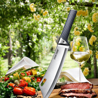SteakChamp koksmes van bovenaf, omringd door groenten en vlees op een snijplank.