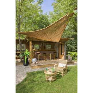 Zonnescherm van kokosvezels boven een houten terras met barkrukken.