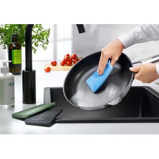 Persoon reinigt een pan met een blauwe siliconen afwasborstel.