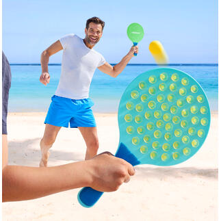 Man speelt op het strand met een ovale paddle en raakt de bal.
