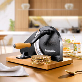 Handmatige broodsnijder op een houten plank met vers gesneden brood.
