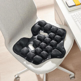 Zwart ergonomisch zitkussen op een stoel.