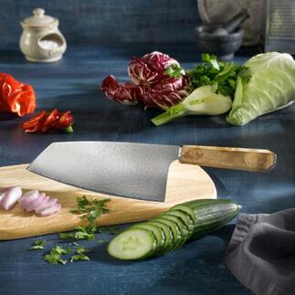 Damast Nakiri-mes op een houten plank, omringd door verse groenten.