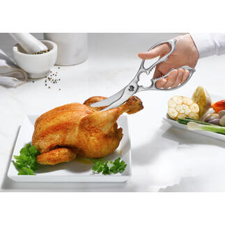 Twee-in-een keuken- en gevogelschaar snijdt een kip op een bord.