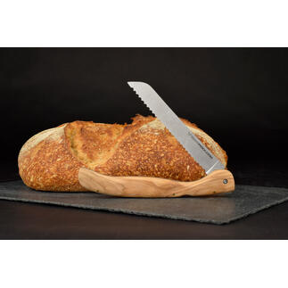 Opvouwbaar broodmes met olijfhouten handvat naast een brood op een zwarte ondergrond.