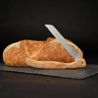 Opvouwbaar broodmes met olijfhouten handvat naast een brood op een zwarte ondergrond.