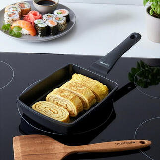 Tamagoyaki-pan met opgerolde eieren naast een sushi-schaal.