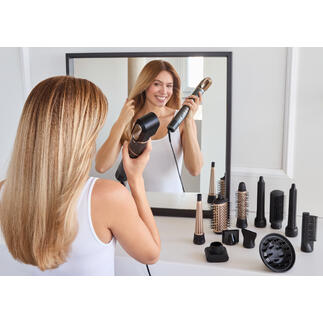 Vrouw stylt haar haar met een 12-in-1 haarstyler voor een spiegel.