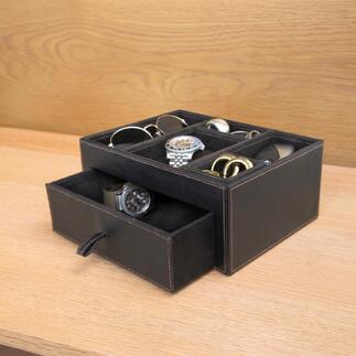 Zwarte leren opbergbox met verschillende accessoires zoals horloges en brillen.