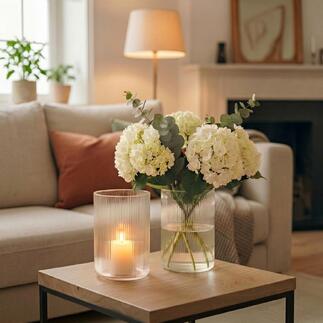 Twee vazen met witte bloemen en licht in een moderne woonruimte.