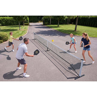 Gezin speelt Pickleball buiten, met net en ballen.