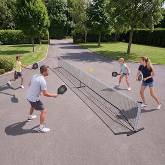 Gezin speelt Pickleball buiten, met net en ballen.