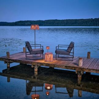Buiten tafel met LED-verlichting aan water, omringd door stoelen.