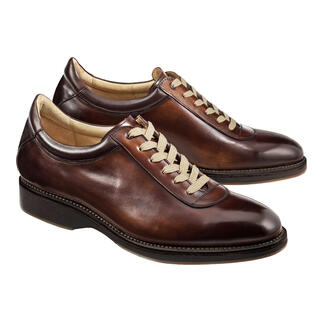 Twee Cordwainer Edelsneakers in bruin op een lichte achtergrond.