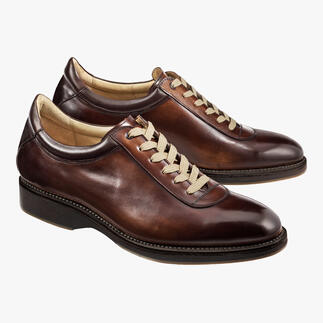 Twee Cordwainer Edelsneakers in bruin op een lichte achtergrond.