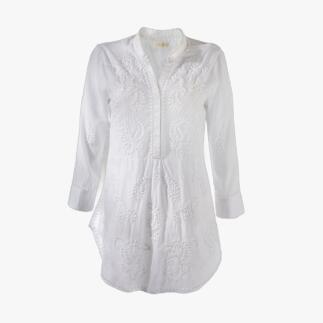 Lichte, geborduurde hippie-blouse in wit aan een kledingstandaard.