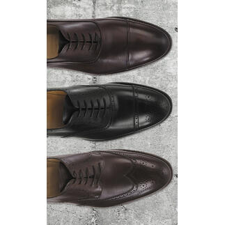 Drie Cordwainer business schoenen in verschillende bruintinten naast elkaar op een stenen oppervlak.