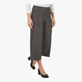 Vrouw in hanf-wijdleg-broek met een elegant top, poseert in de stad.