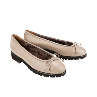 Twee beige lamsleer ballerina's naast elkaar op een lichte achtergrond.
