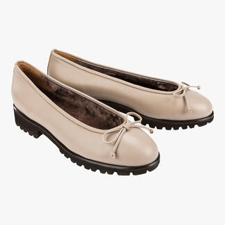 Twee beige lamsleer ballerina's naast elkaar op een lichte achtergrond.