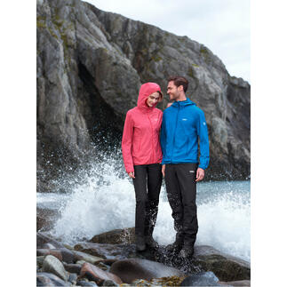 Koppel in outdoor kleding, een persoon draagt een roze softshell jack, de ander in een blauwe jack naast woelig water.