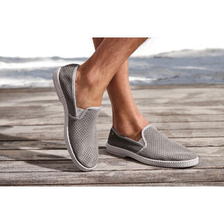 Grijze leren slippers met geperforeerd oppervlak op houten terras.