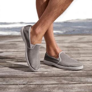 Grijze leren slippers met geperforeerd oppervlak op houten terras.