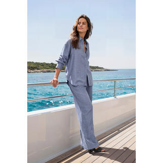 Vrouw in blauwe blouse en broek staat op een boot in de zee.