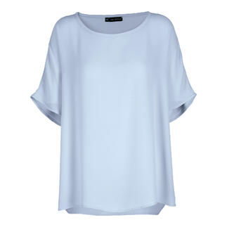 Lichtblauwe T-shirt-blouse met een losse pasvorm en korte mouwen op een neutrale achtergrond.